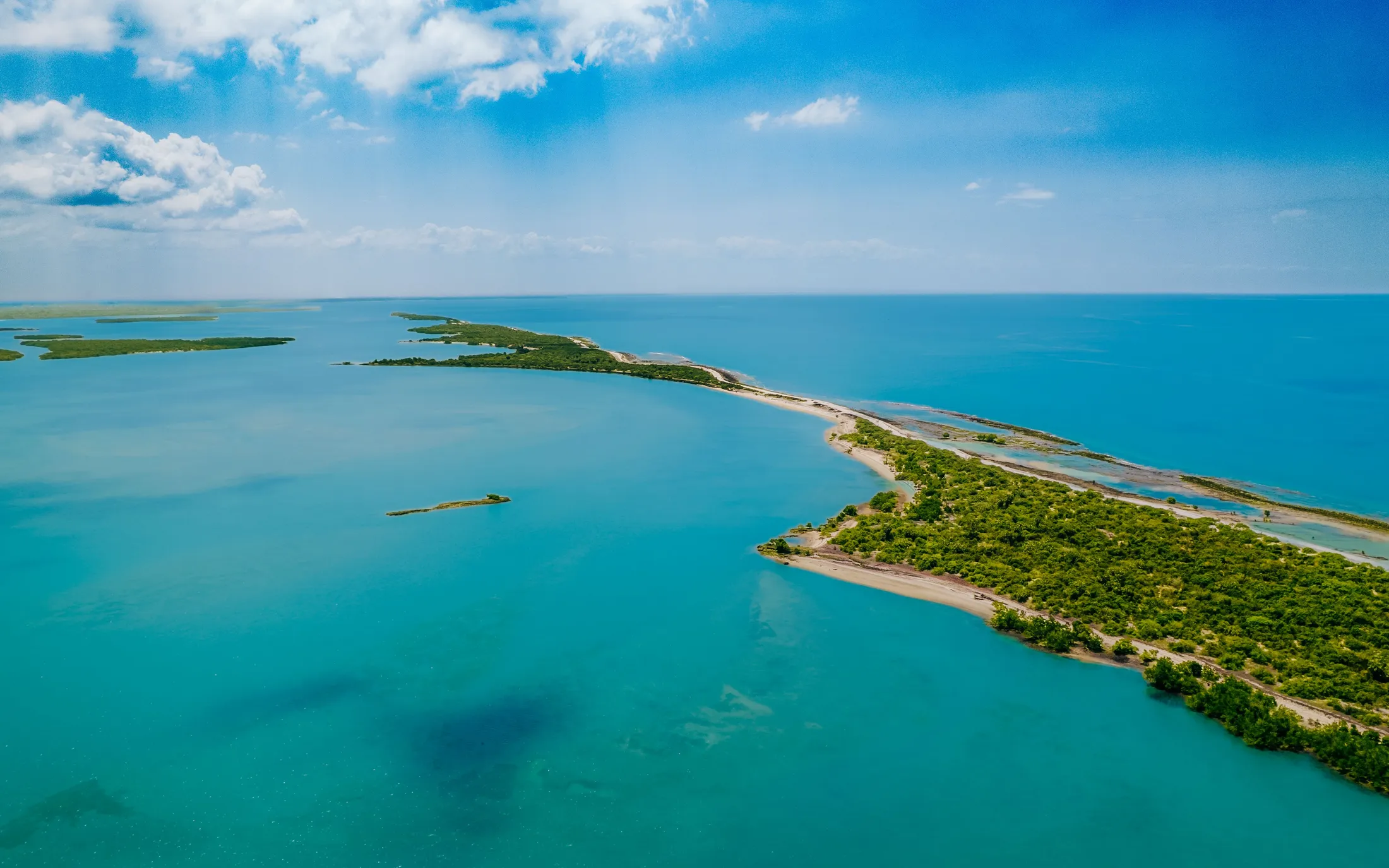 An aerial view of a coastline and shallow turquoise water