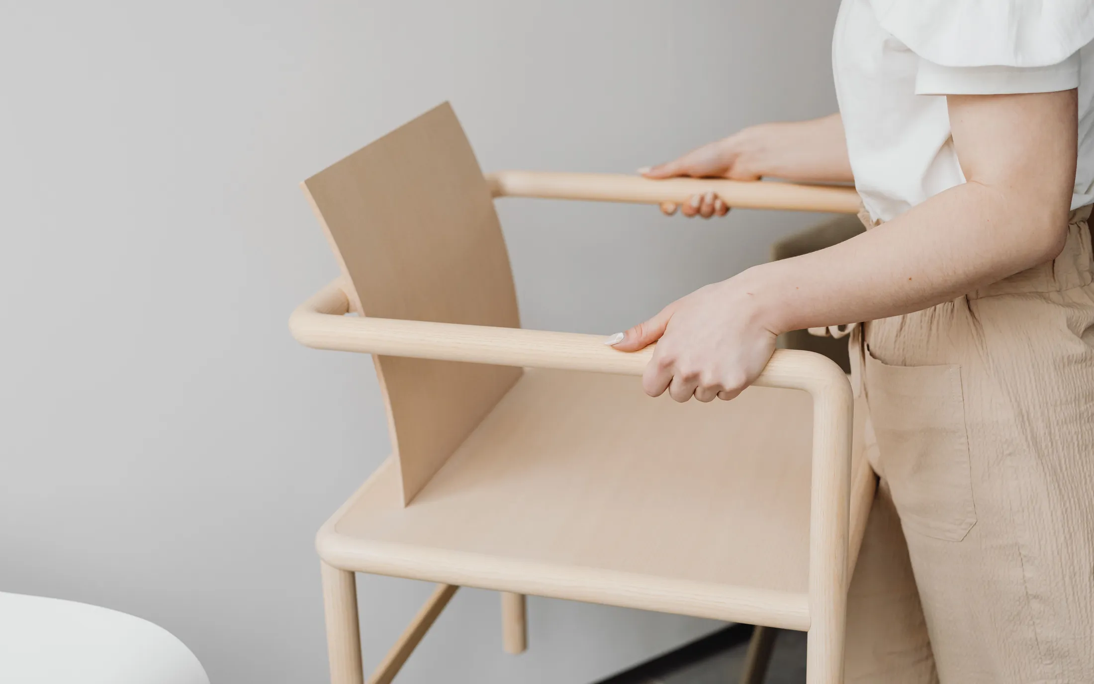 Hands fitting the back panel of a timber chair
